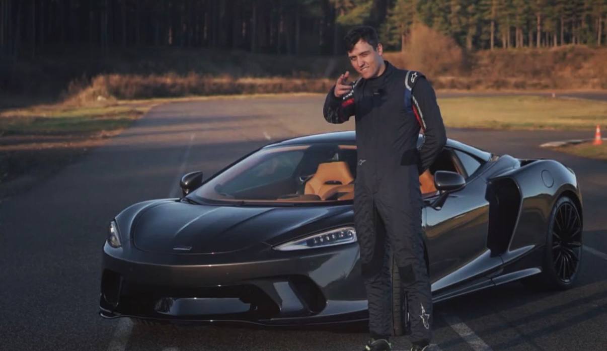 Danila in a racing suit beside a McLaren GT on a track