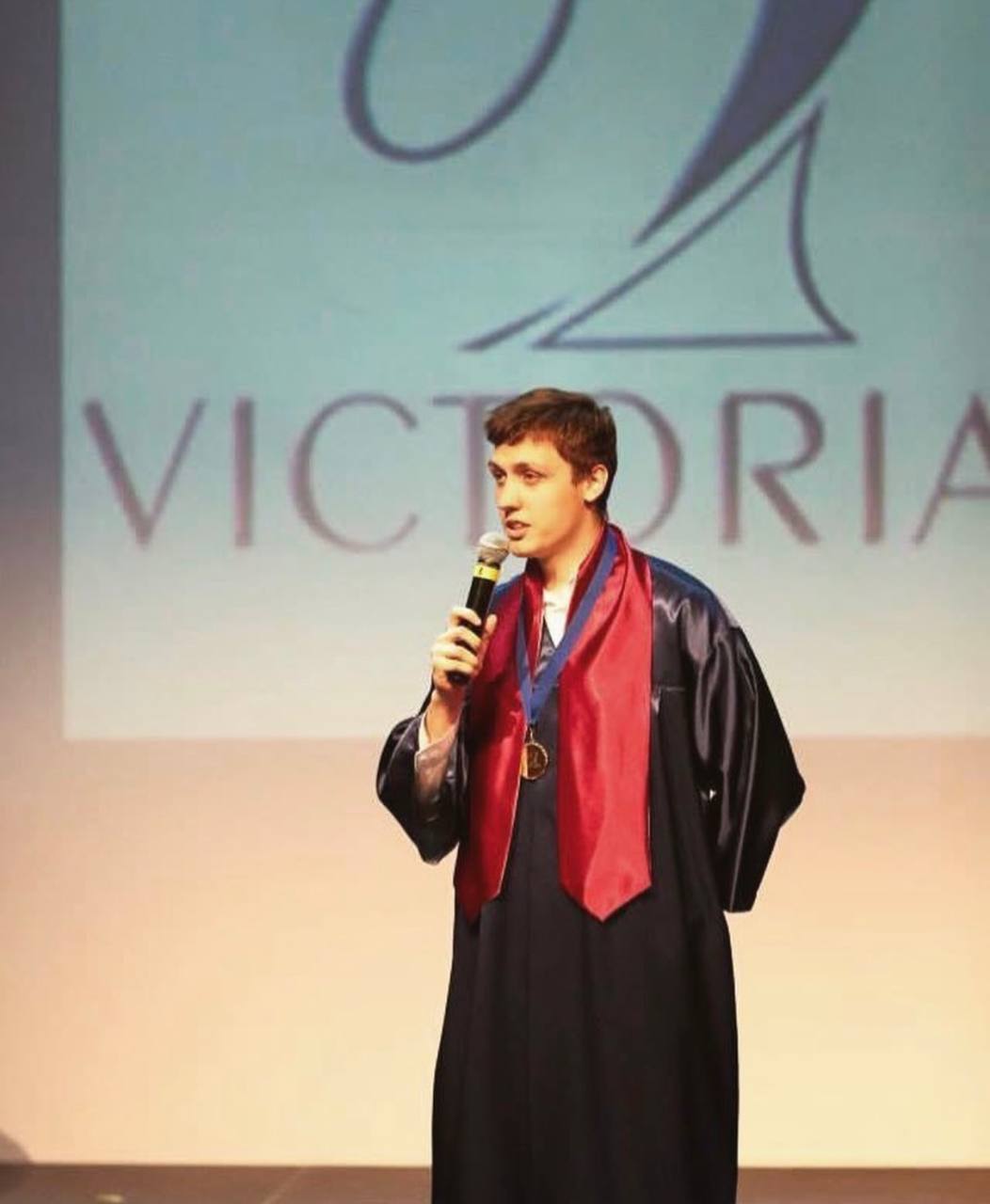 Danila speaking on stage with a microphone